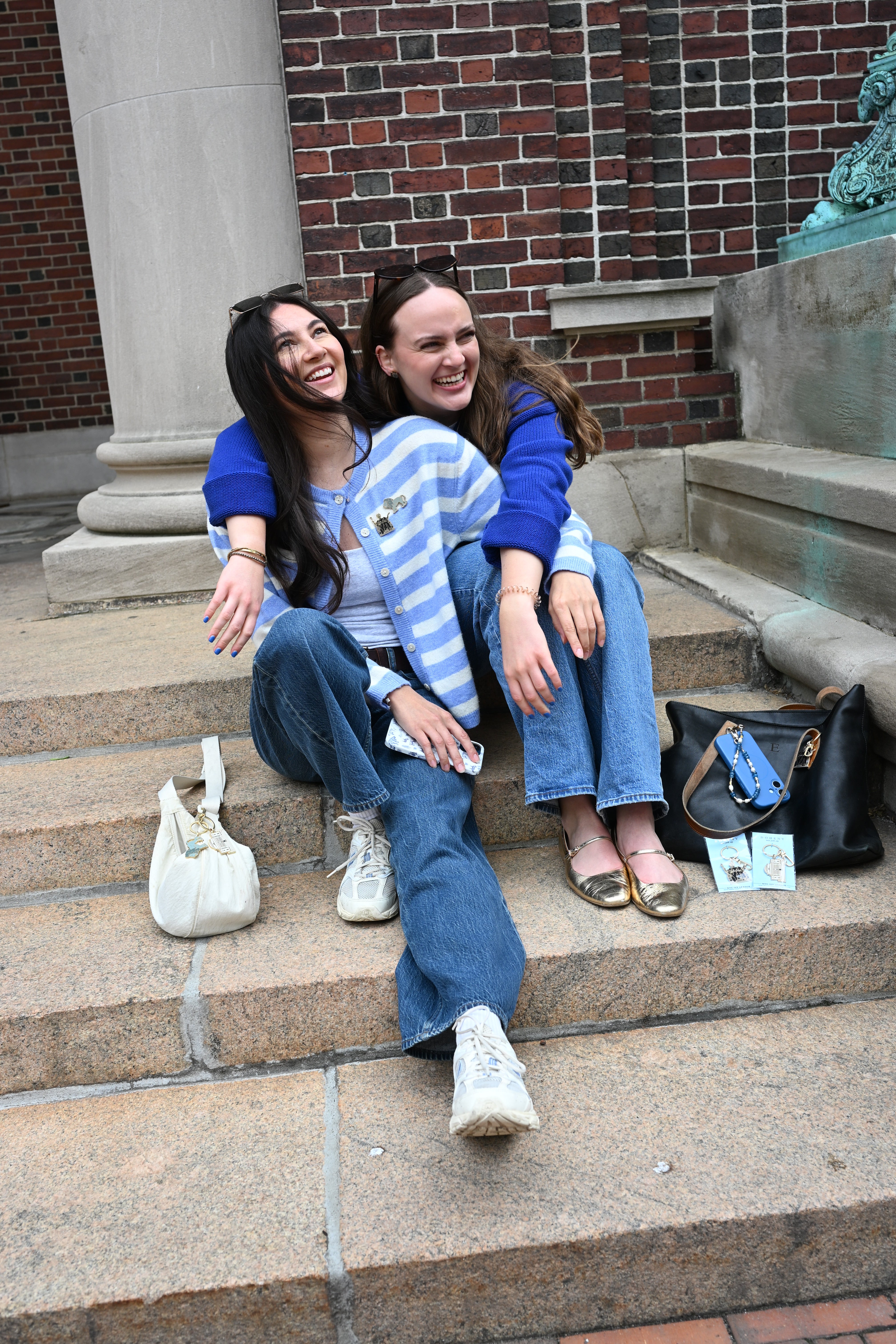 Two people sitting on steps with a brick building in the background