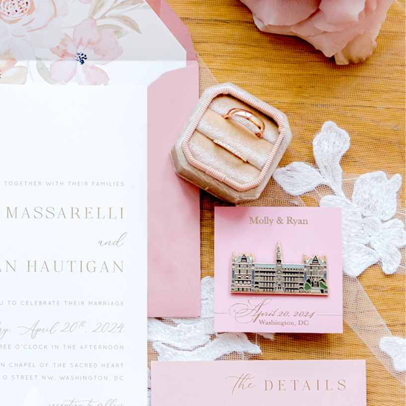 Wedding invitation set with pink envelopes and cards on a wooden surface with flowers.